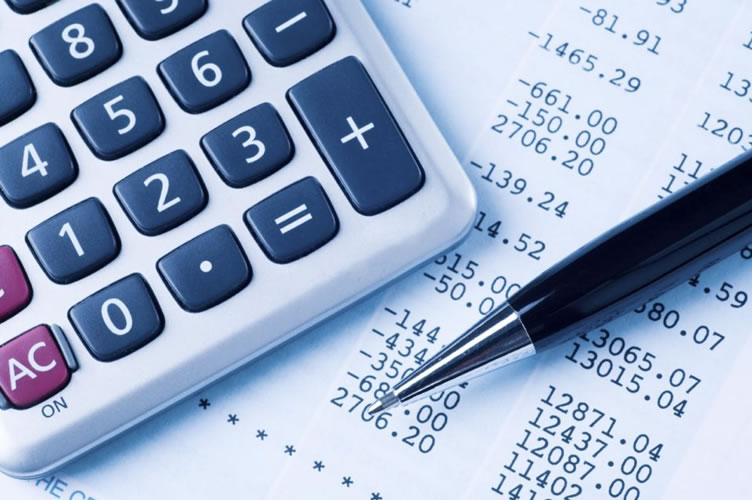 Uma calculadora, nota fiscal ao fundo e uma caneta. A gestão financeira é fundamental para o gerenciamento de uma imobiliária.